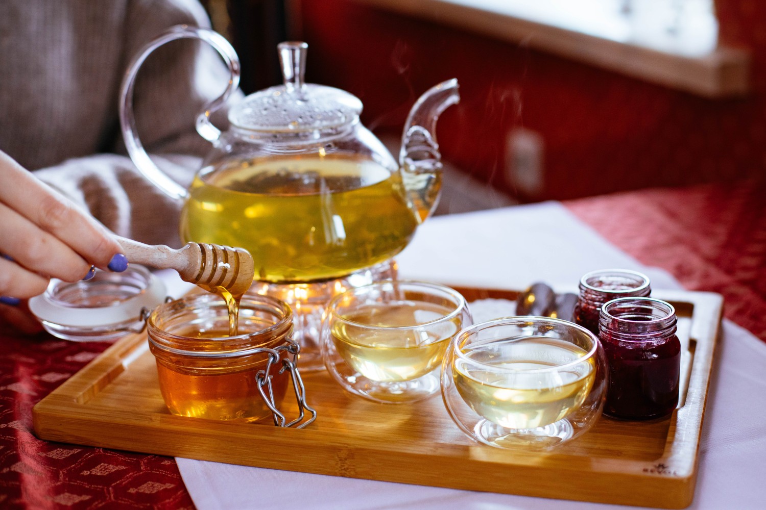 Treating a Cold at Home 1 A person holding a honey stick next to a teapot